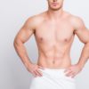 Cropped close up photo of shirtless sexy tempting muscular attractive man's torso, man is keeping hands on hips isolated on gray background copy-spac
