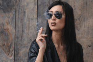 girl in a leather jacket and sunglasses smoking a cigarette