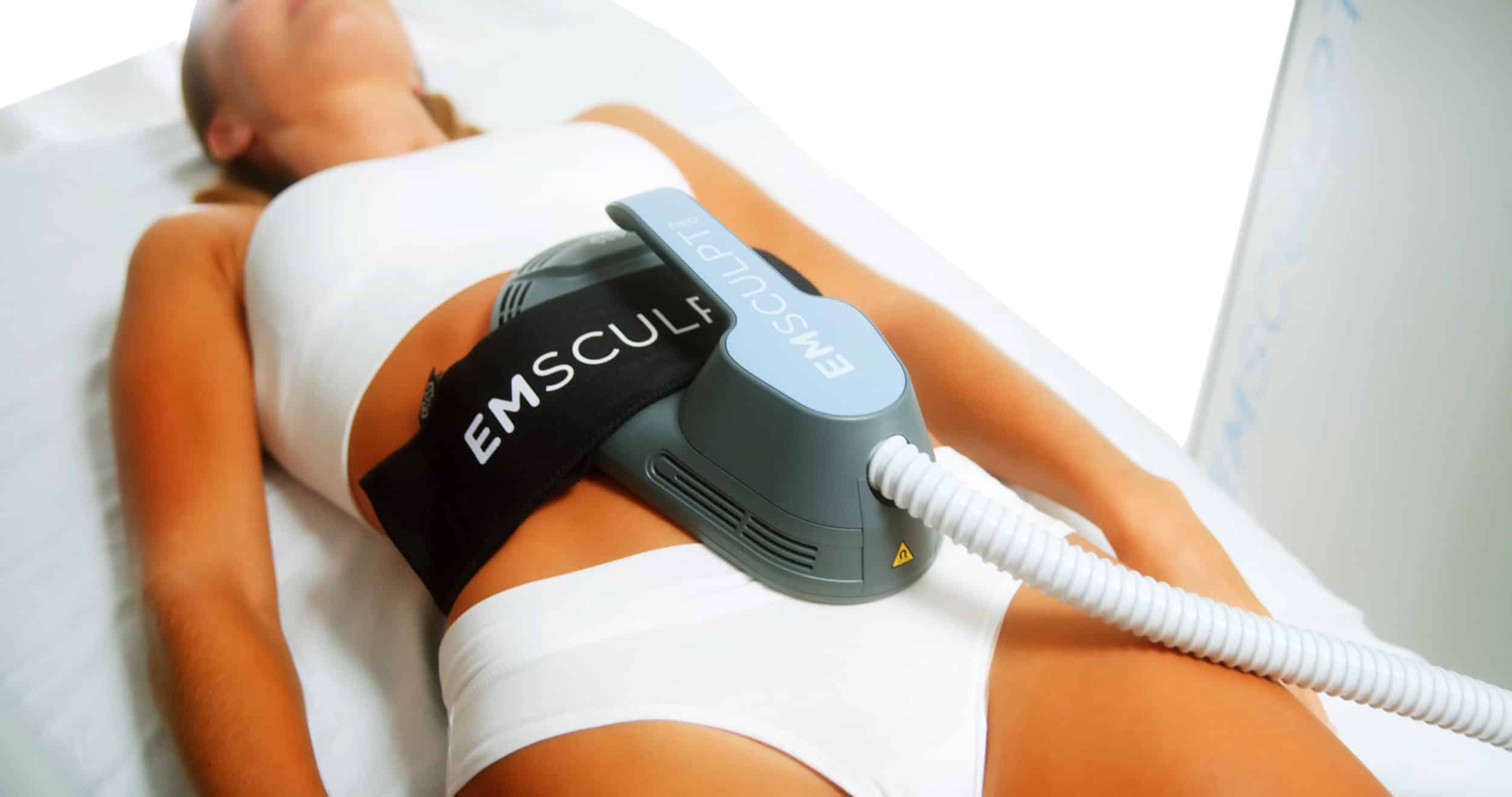 woman laying down with emsculpt neo non-surgical body contouring device on stomach