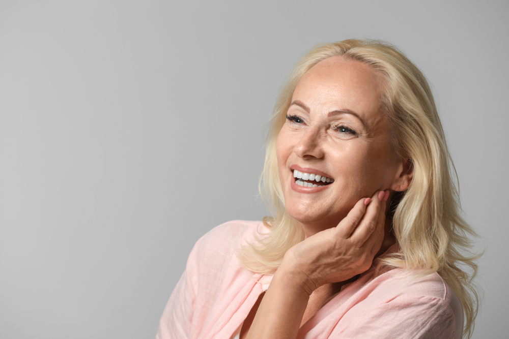 Beautiful mature woman smiling with radiant skin after EMFACE treatment.