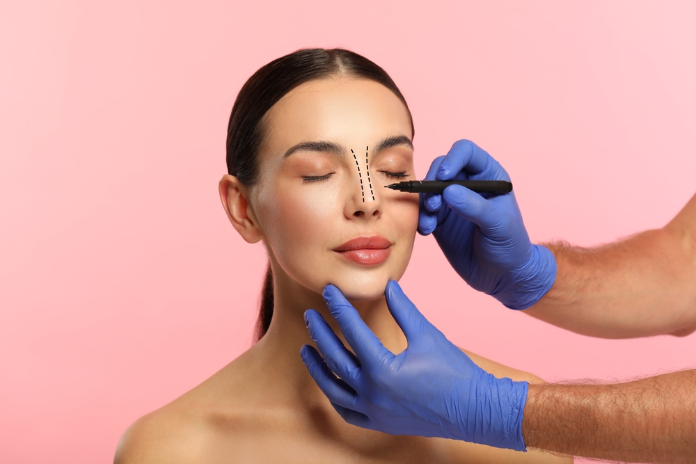 Woman receiving facial assessment before non-surgical rhinoplasty treatment.