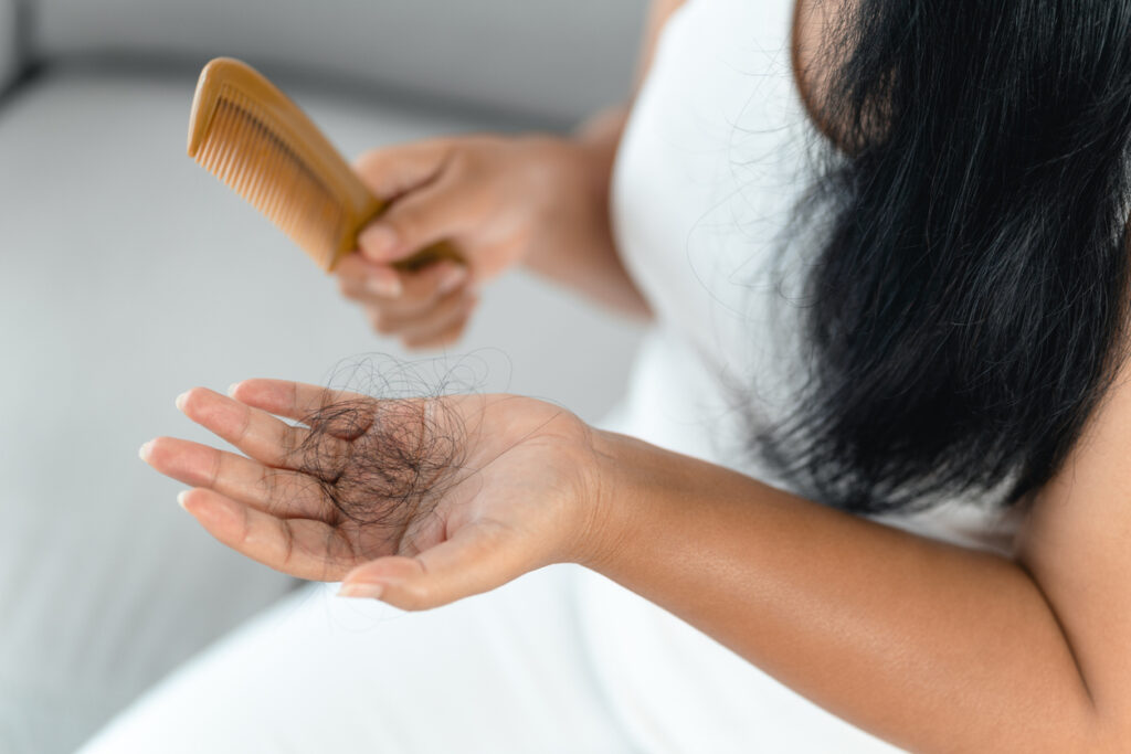 Woman noticing hair shedding while brushing.